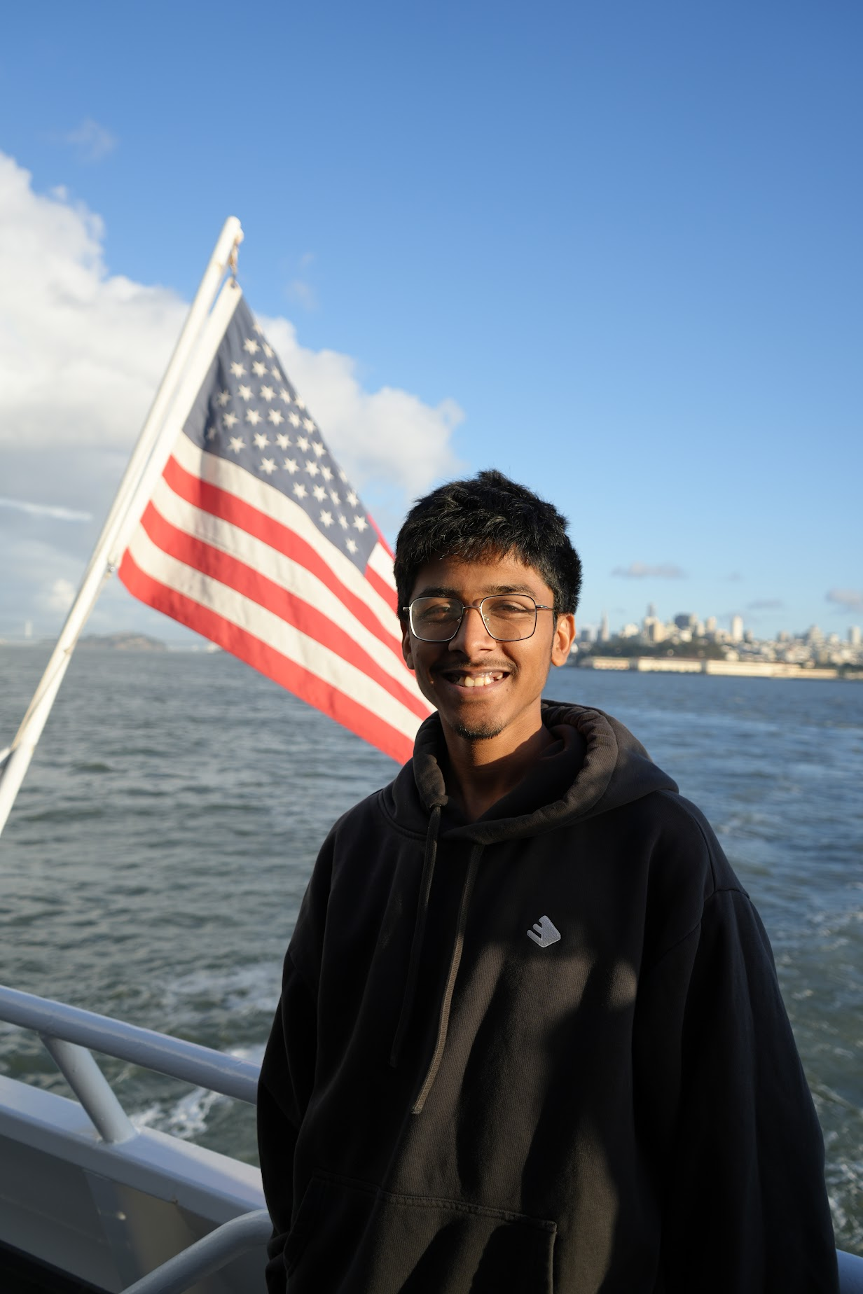 Dhravya Shah on a boat with San Francisco in the background
